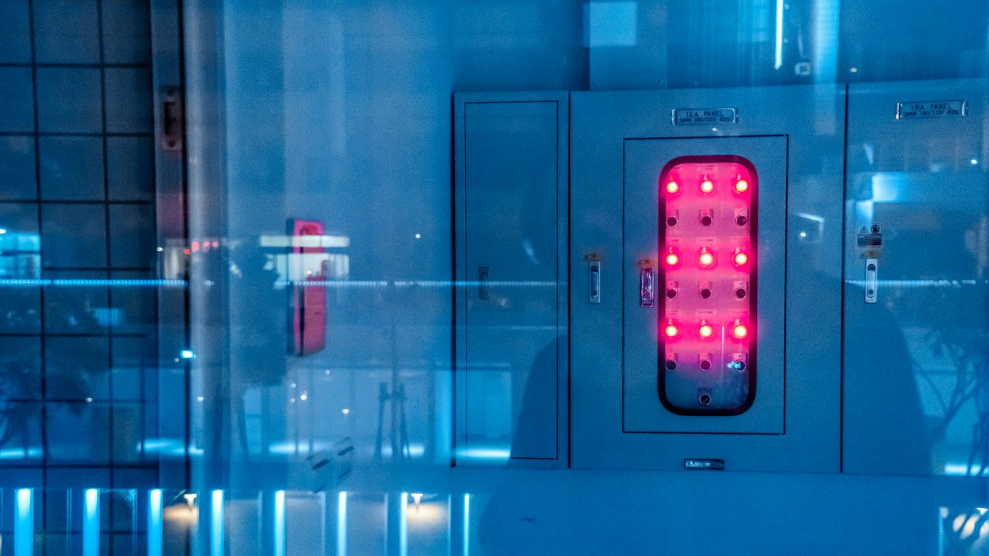 Glowing red indicator lights on an industrial electrical control panel.